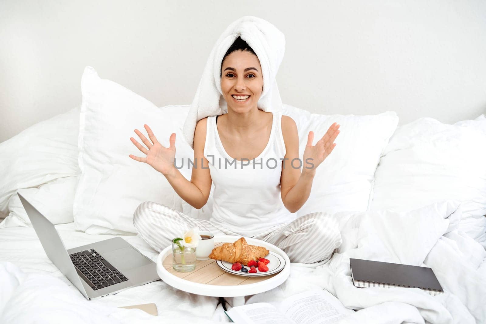 Happy young woman of Spanish appearance and received a surprise in the form of breakfast in bed. The girl raised her hands up in surprise and happiness. The best start to the work day.