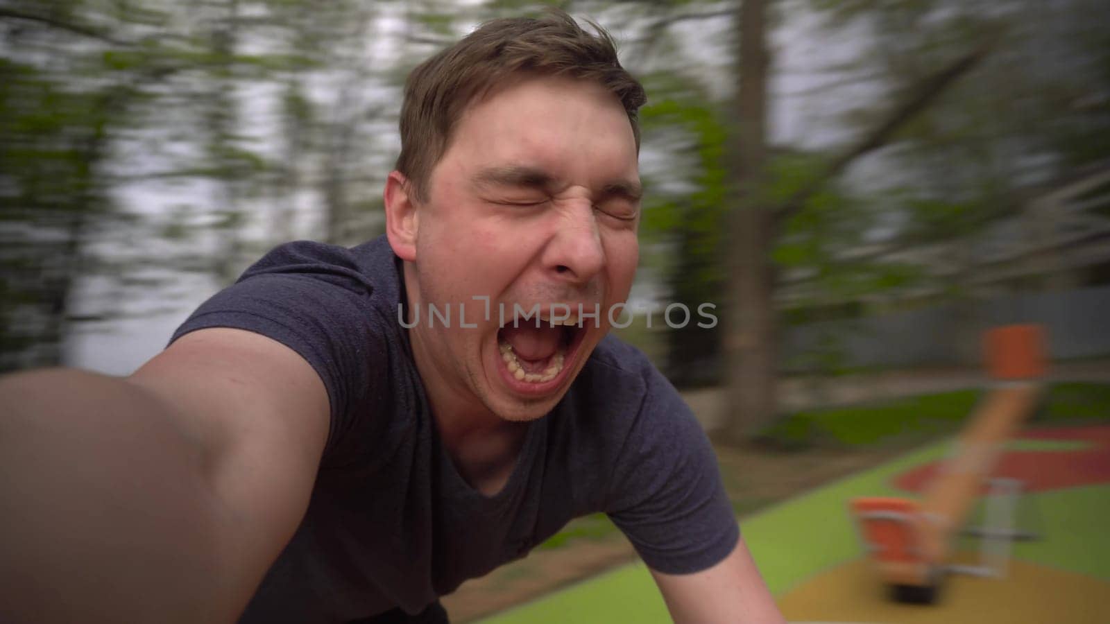 A young man is spinning on a carousel. A man has fun and shouts at the attraction close-up. First-person view. 4k
