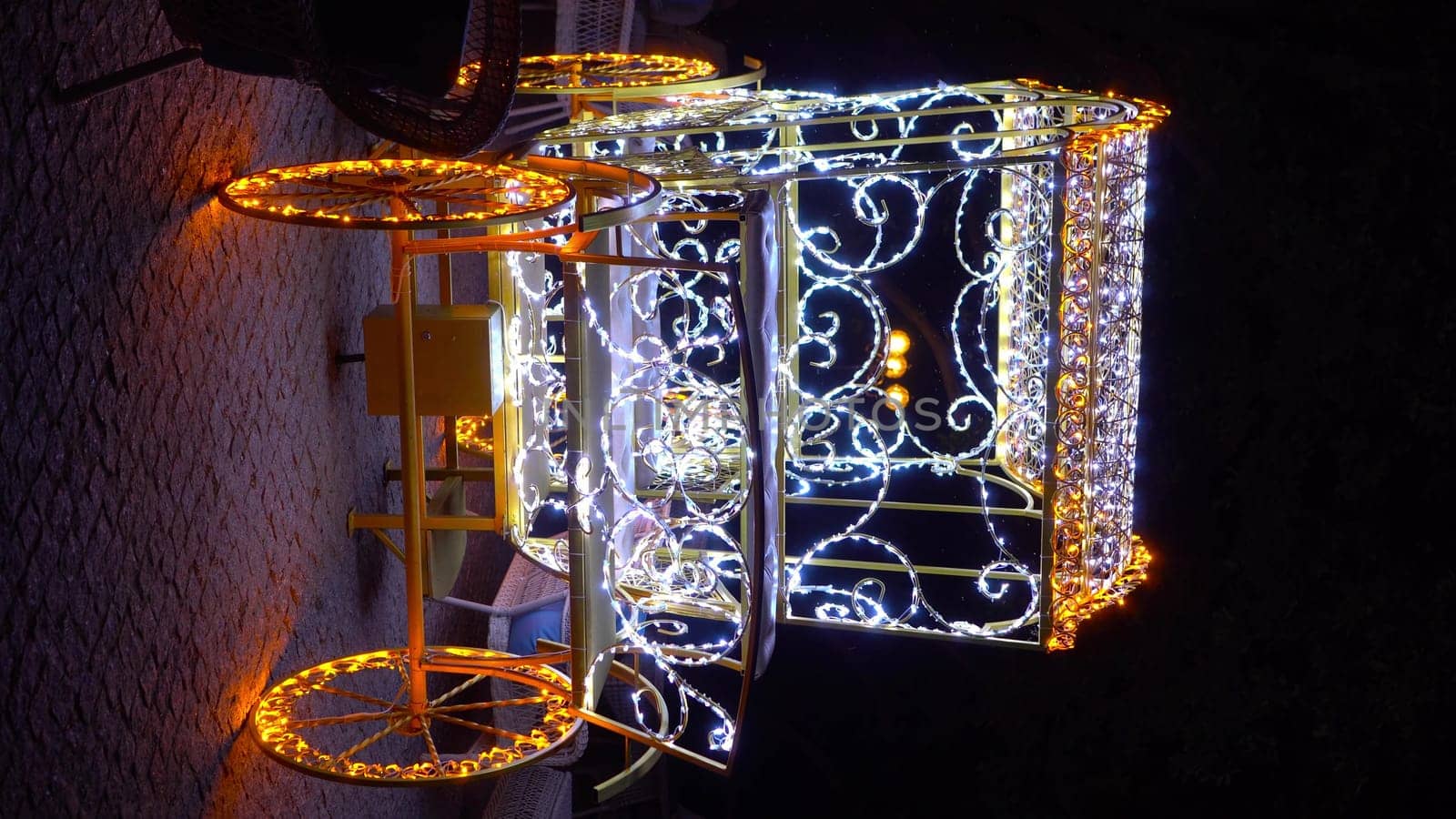 An old carriage in garlands shines at night. Decoration in the form of a carriage with light bulbs on the summer terrace in a cafe. Vertical video. 4k