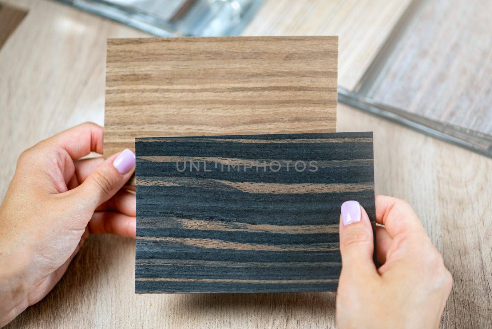 A woman is holding samples of different colors in her hands at the same time and choosing pieces of colored wood to choose a floor. by SERSOL