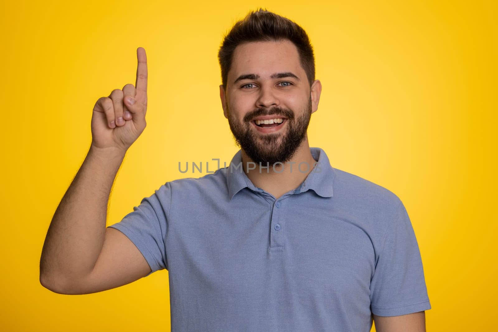 Eureka. Inspired young caucasian man pointing finger up with open mouth, having good idea, plan, startup, showing inspiration motivation gesture, problem solution. Bearded guy on yellow background
