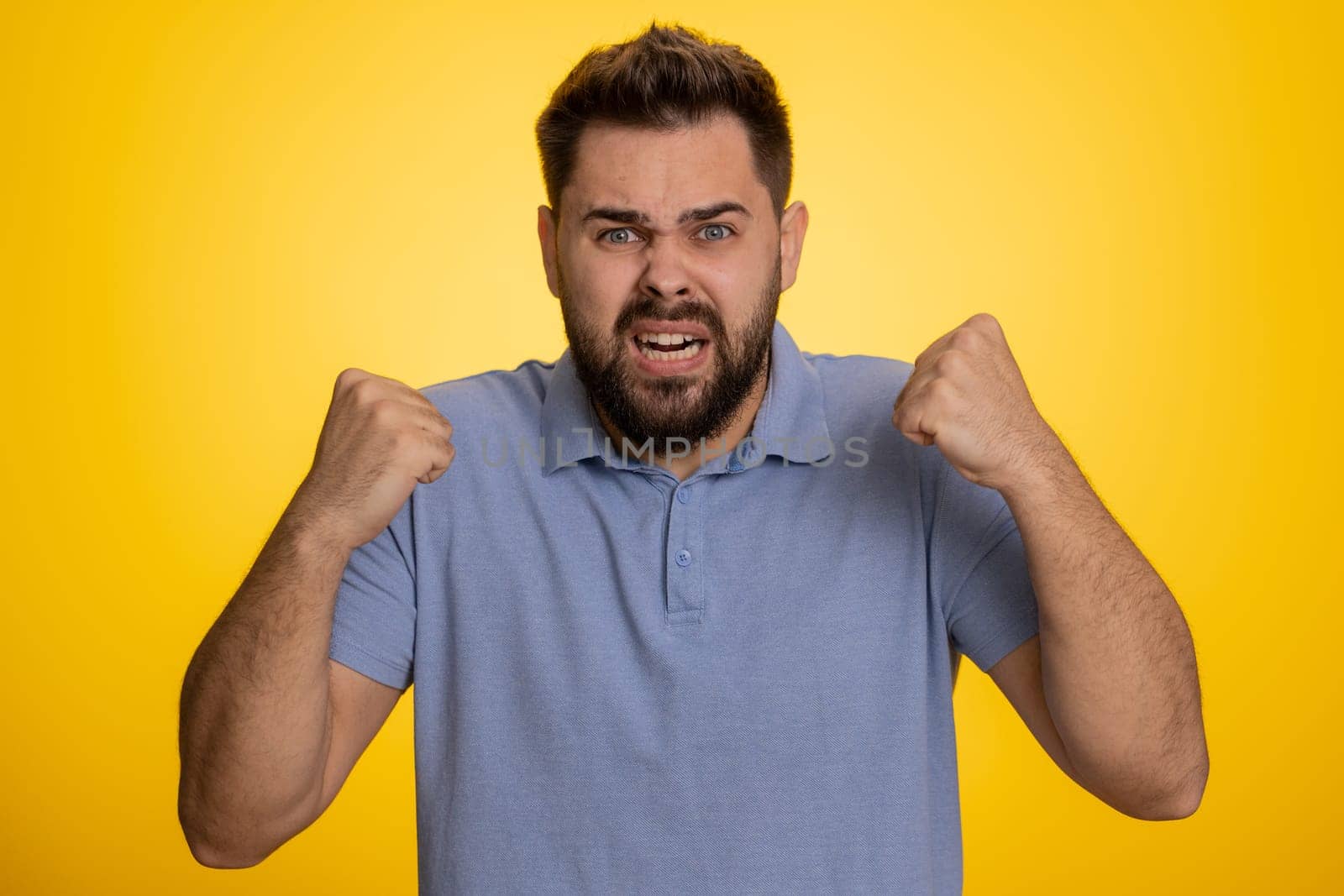 Caucasian man in t-shirt screams yell from stress tension problems feels horror hopelessness fear panic surprise shock expresses gestures rage. Handsome young guy isolated on yellow studio background