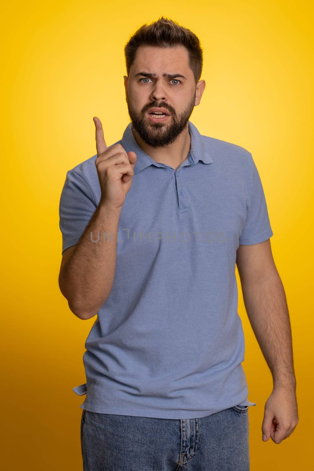 Quarrel. Displeased young caucasian man gesturing hands with irritation and displeasure, blaming scolding for failure, asking why this happened. Bearded adult guy isolated on yellow studio background