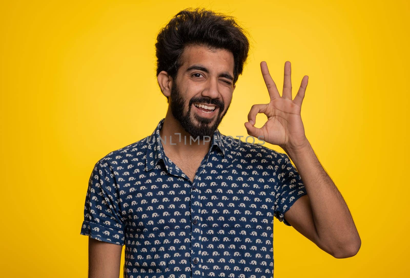 Ok. Joyful happy indian man in shirt looking approvingly at camera showing approve feedback gesture like sign positive something good. Handsome guy alone on yellow background. People sincere emotion