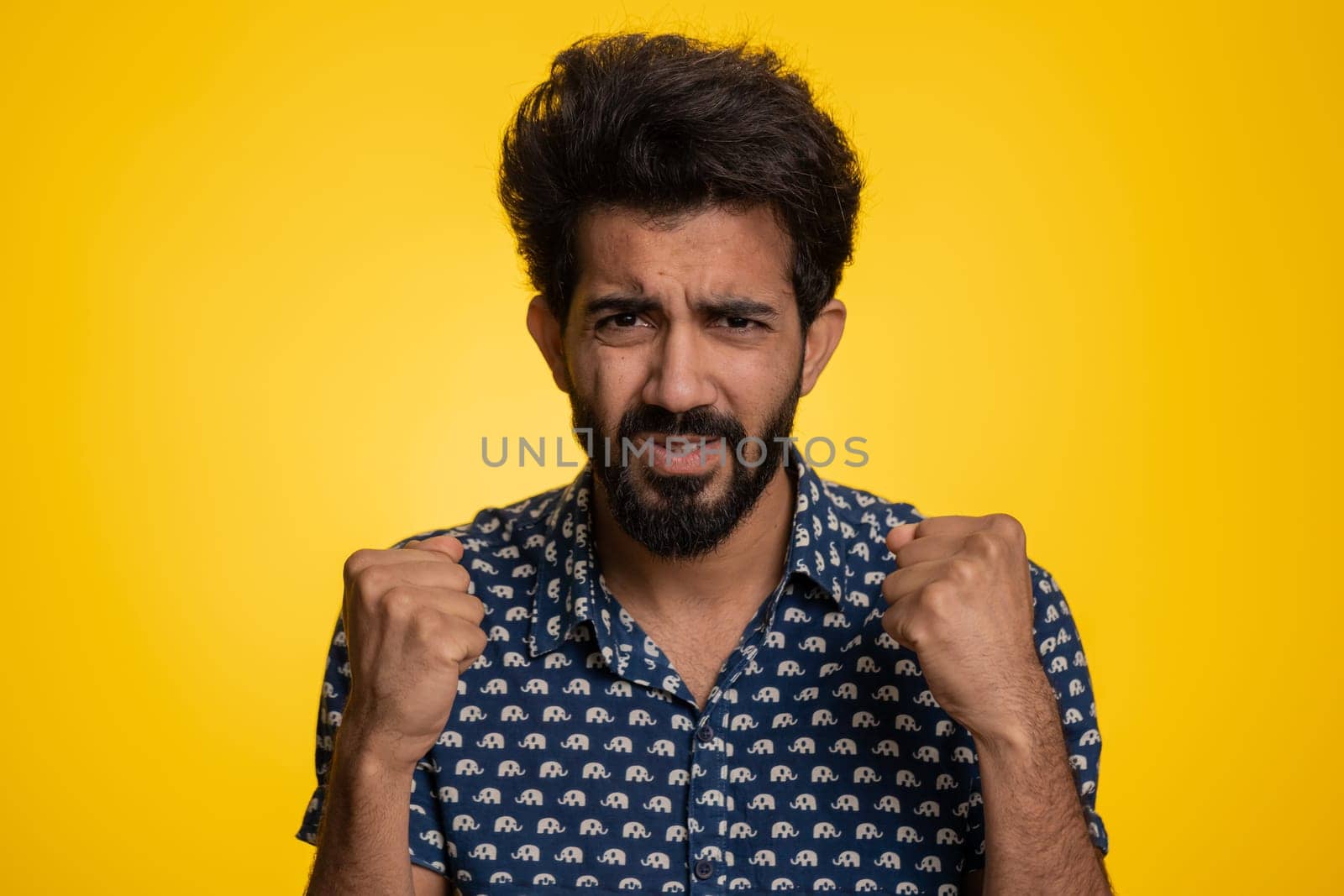 Indian man in shirt screams yell from stress tension problems feels horror hopelessness fear panic surprise shock expresses gestures rage. Handsome hindu guy isolated on yellow studio background