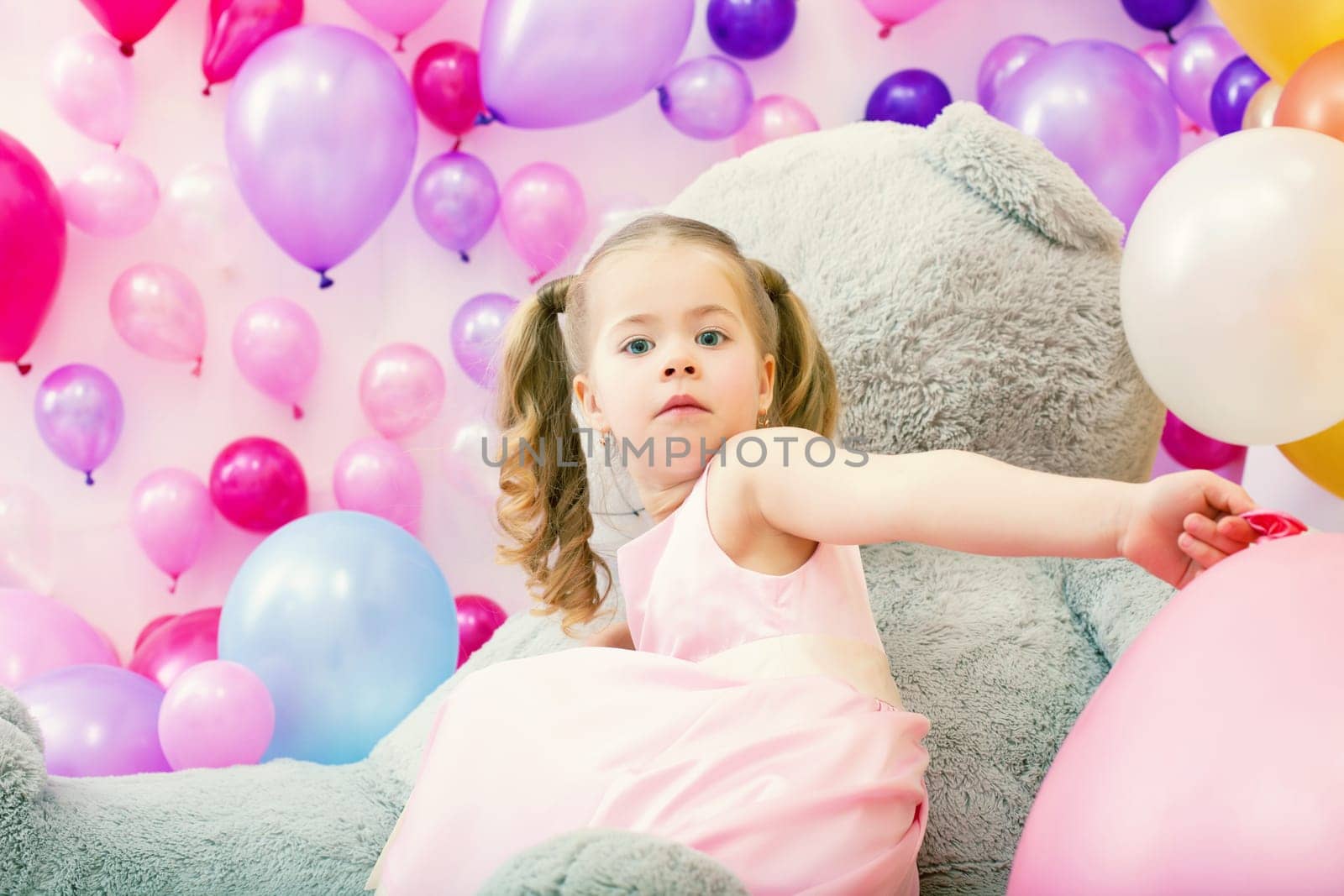 Surprised girl posing at camera with pink balloons