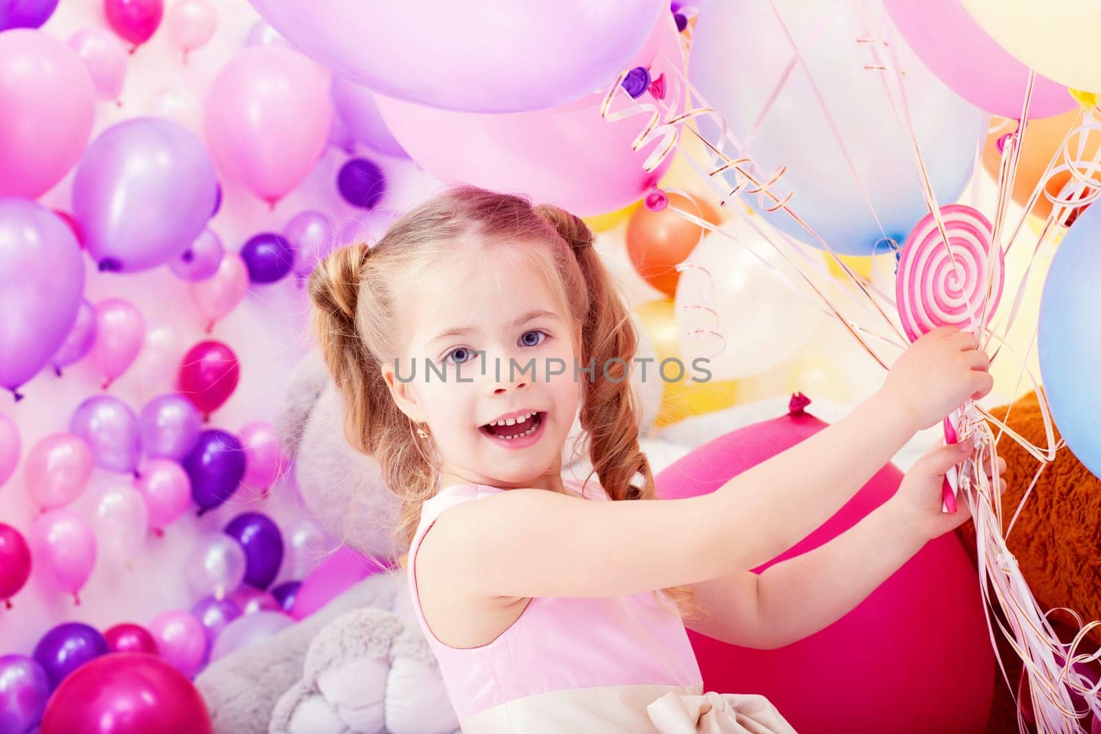 Merry little girl posing with bunch of colorful balloons