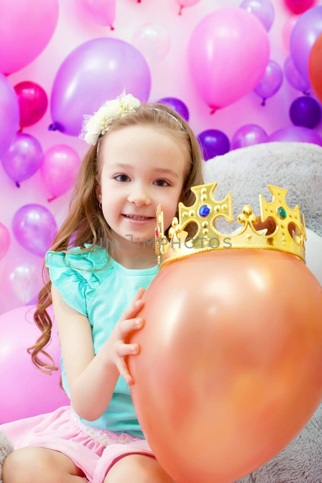 Image of cheerful girl playfully put crown on balloon