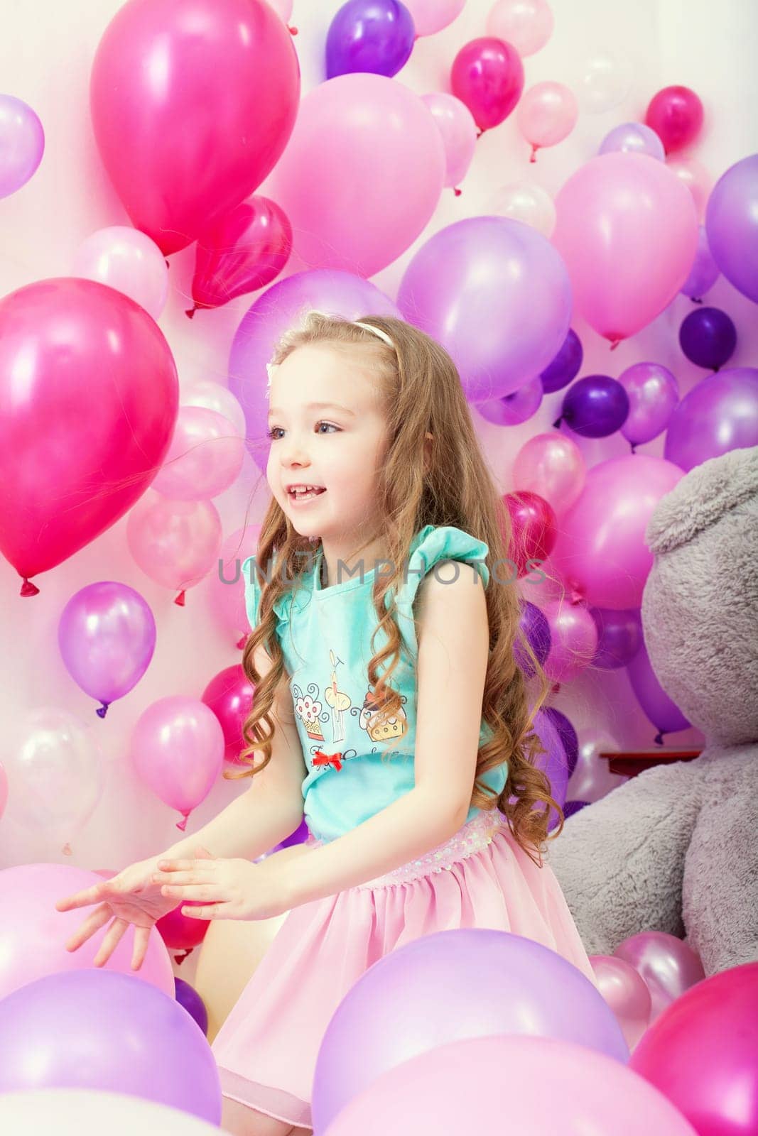 Studio shot of cute little girl playing among balloons