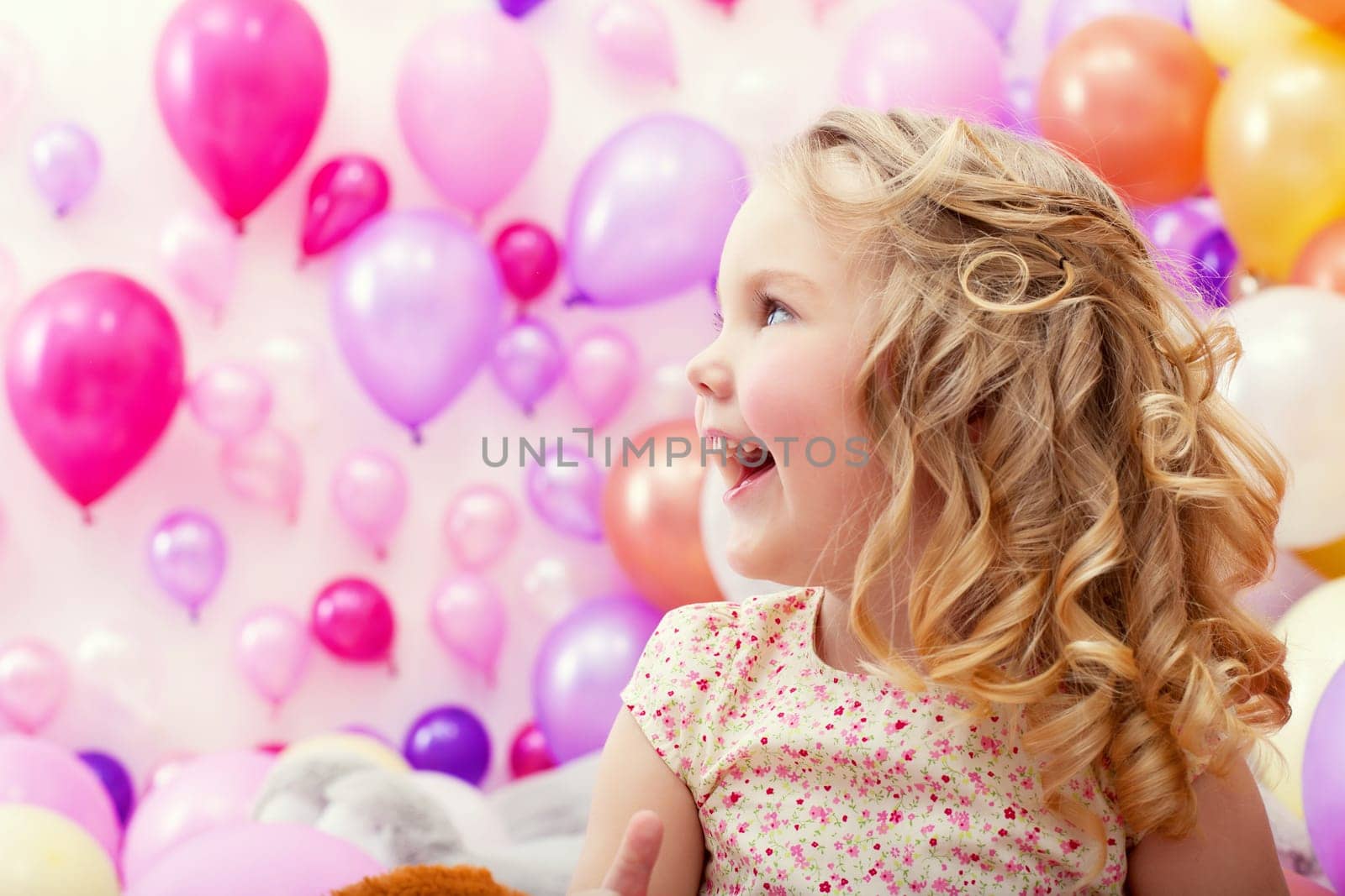 Portrait of adorable cheerful girl on balloons background