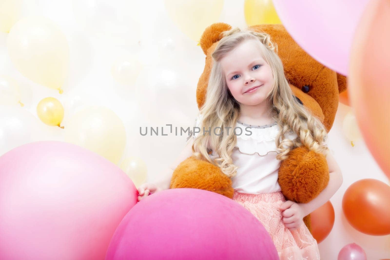 Image of smiling blonde girl playing with teddy bear