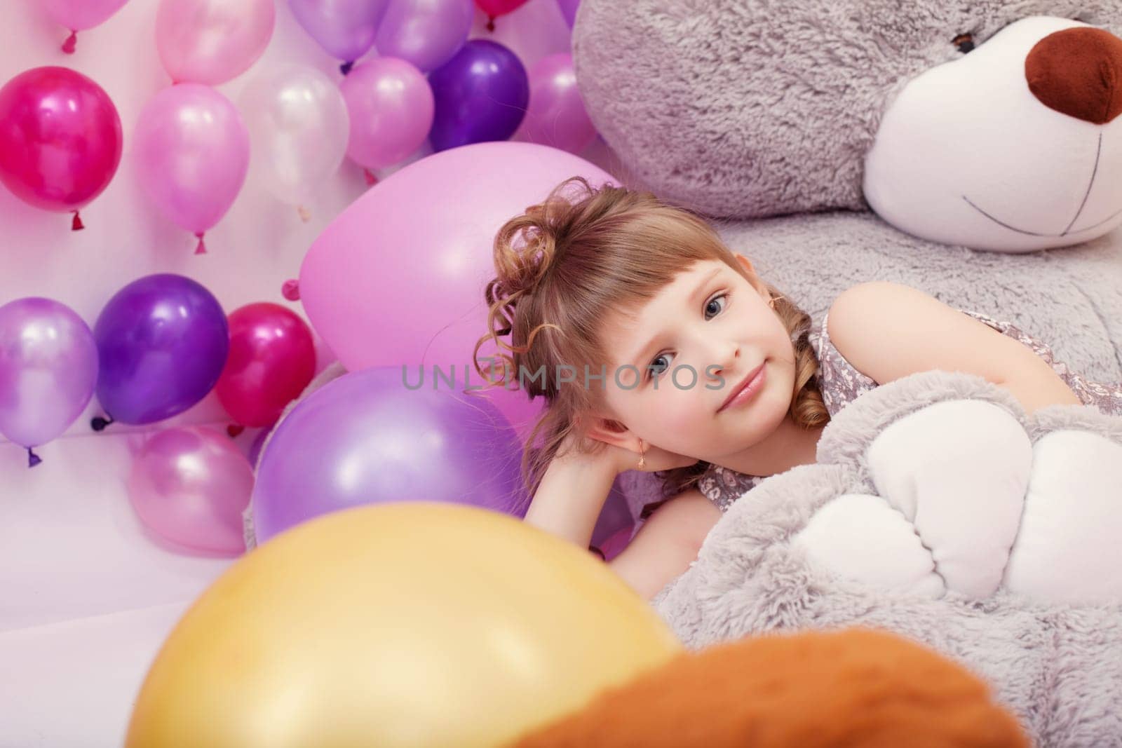 Image of funny little girl posing lying on big plush bear