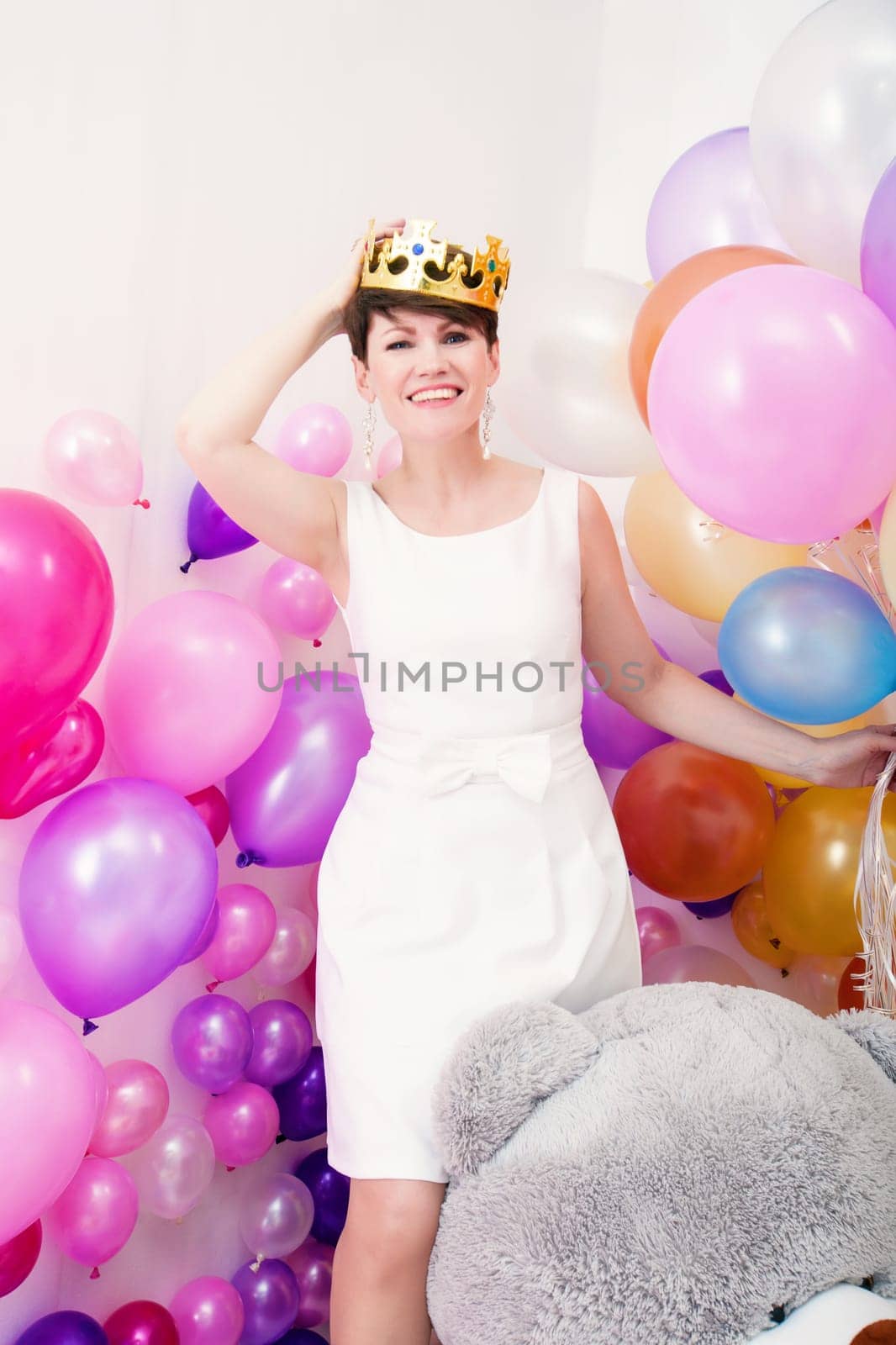 Image of cheerful adult woman tries on toy crown