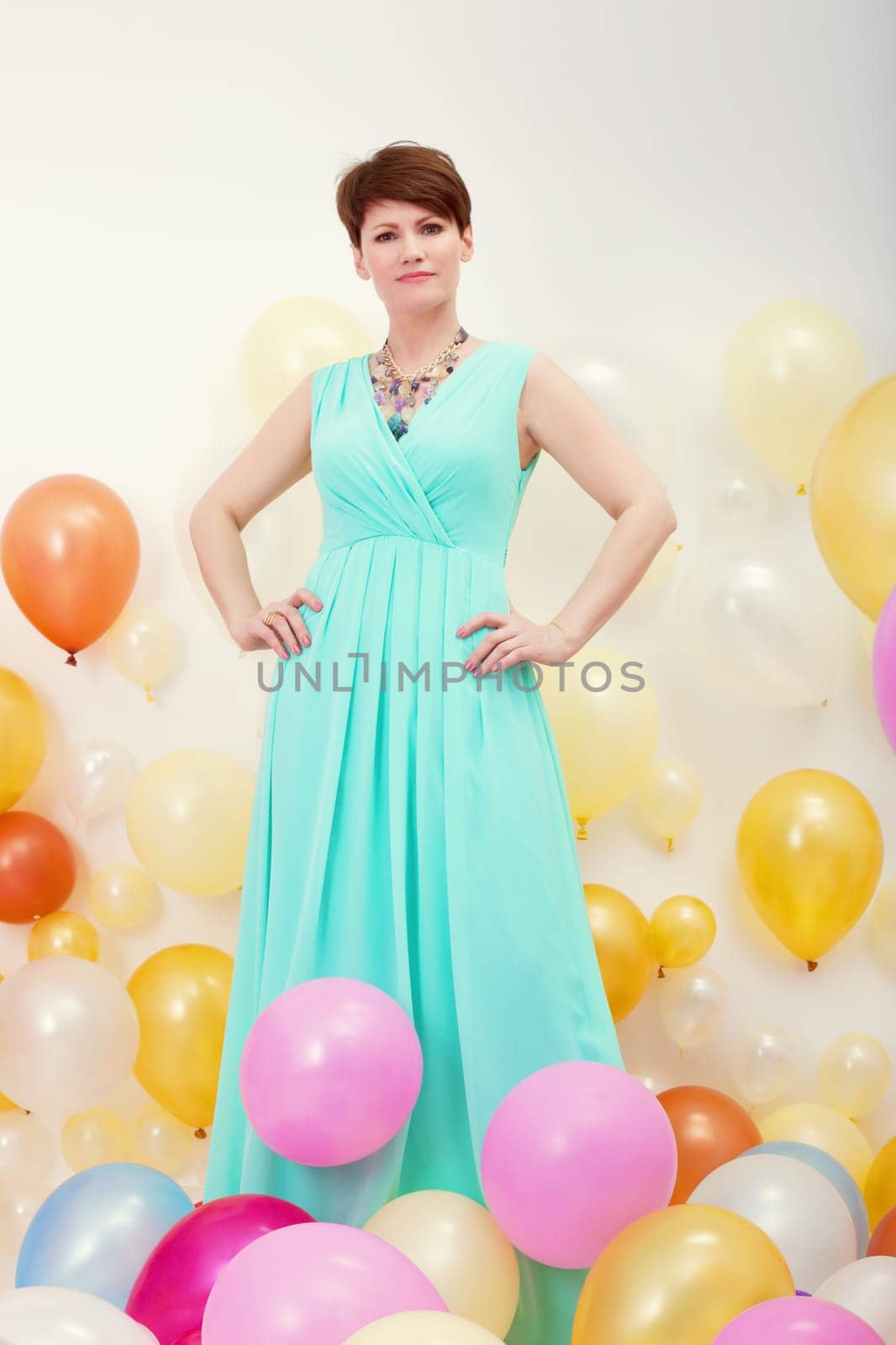 Sexy middle-aged model posing in elegant turquoise dress