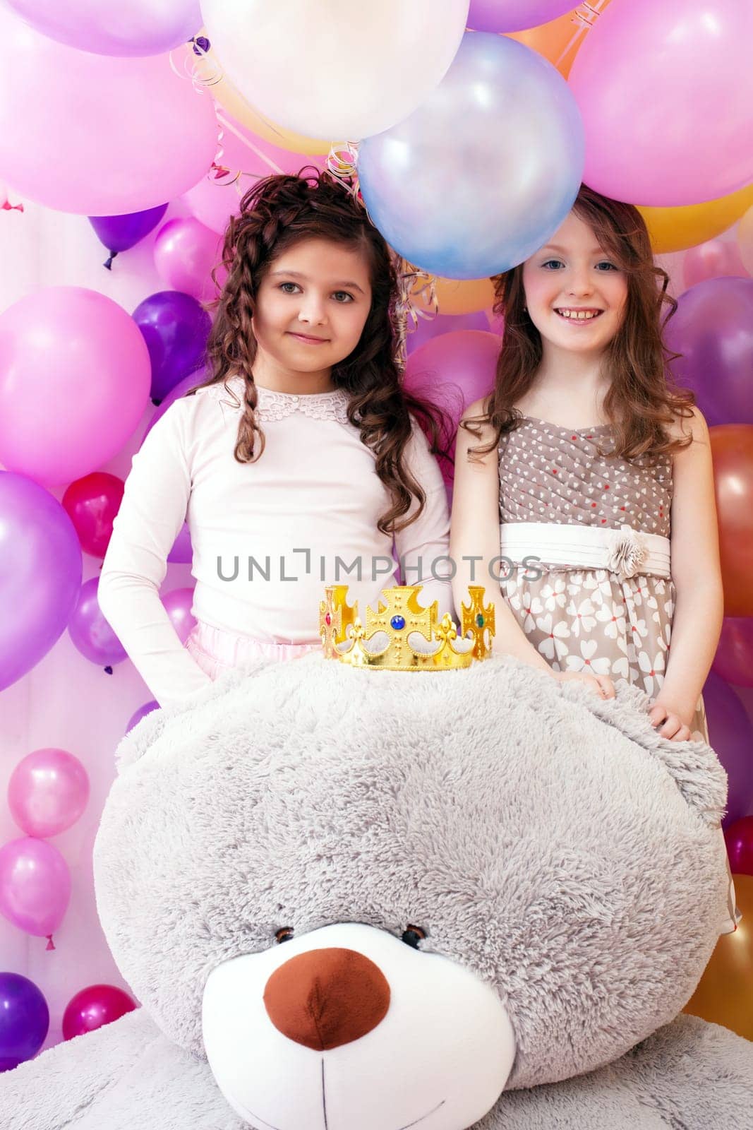 Portrait of two smiling cute sisters and big teddy bear