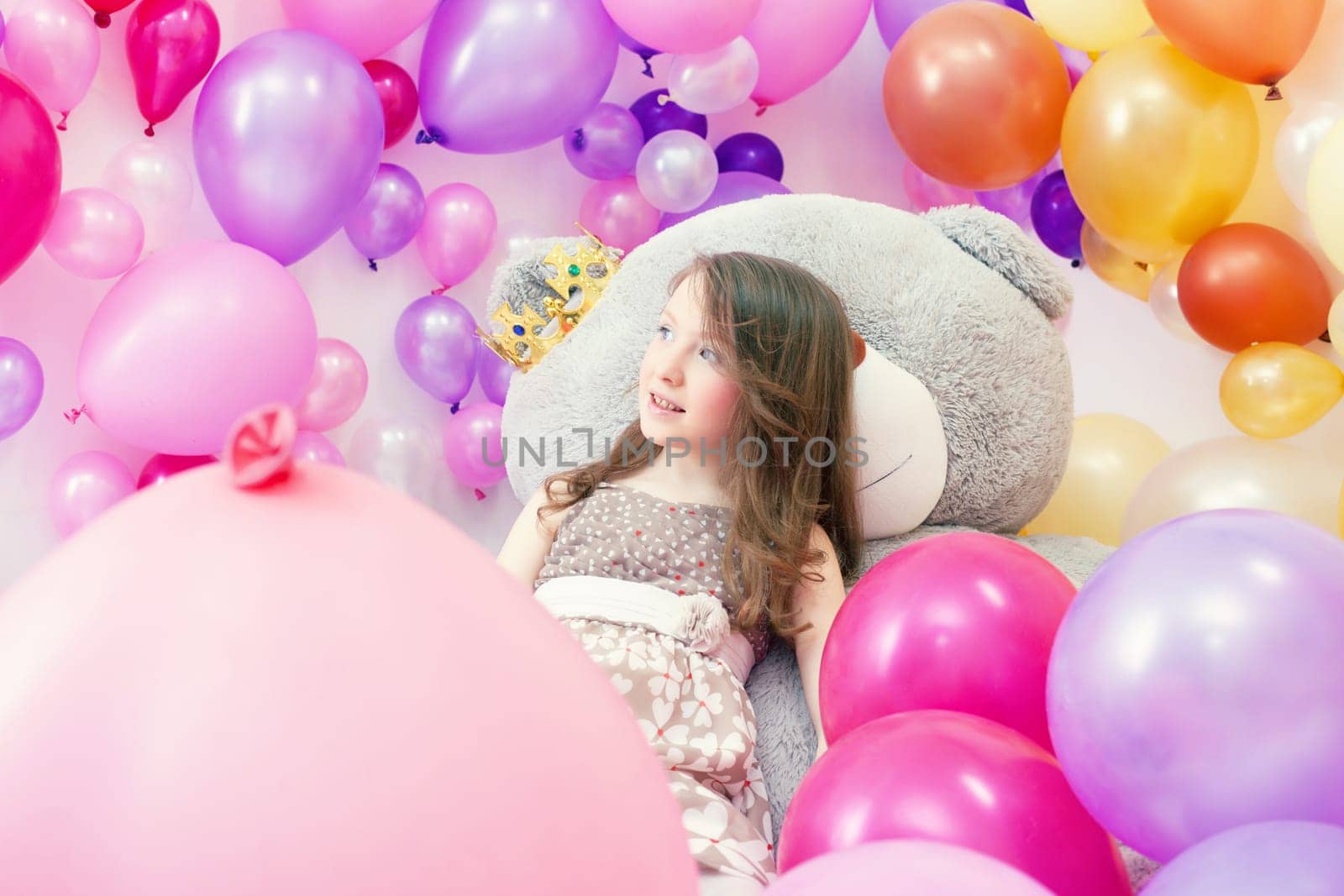 Image of smiling little lady posing lying on big teddy bear