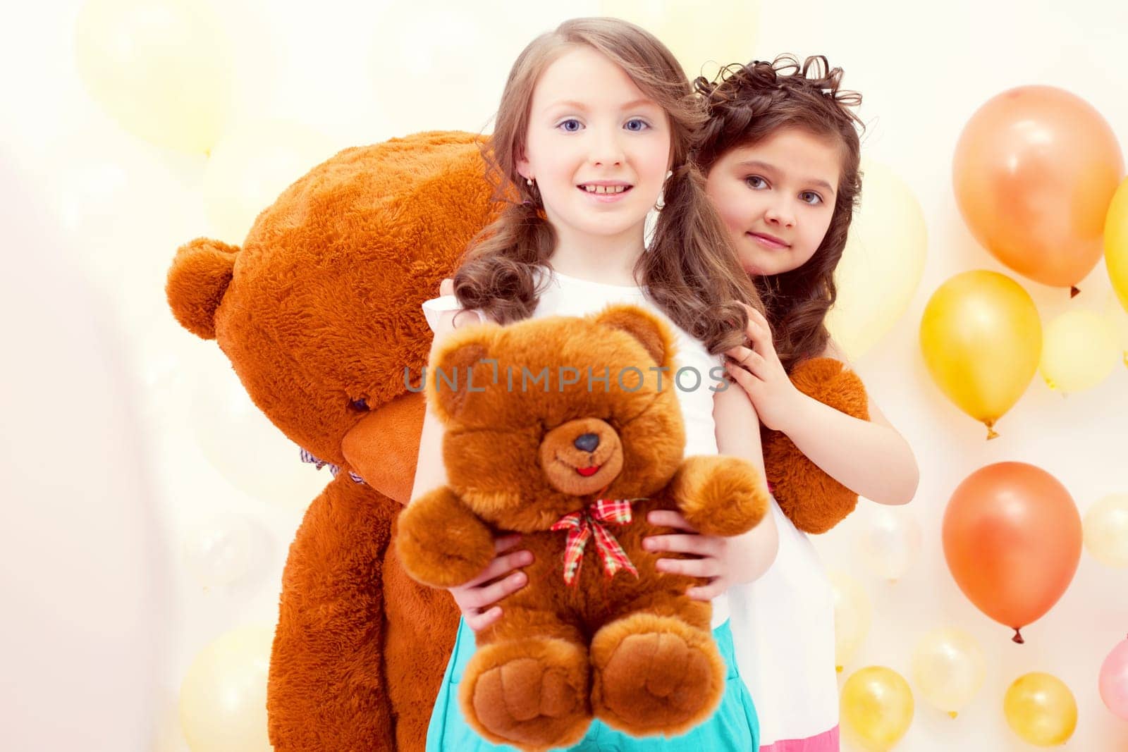 Enchanting sisters posing with teddy bears in playroom