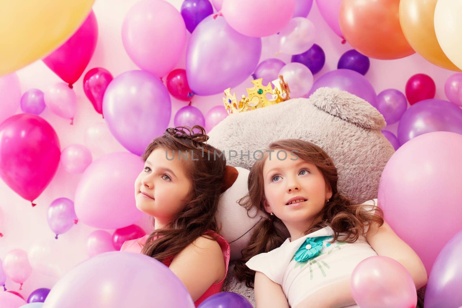 Dreamy little sisters posing lying on big teddy bear