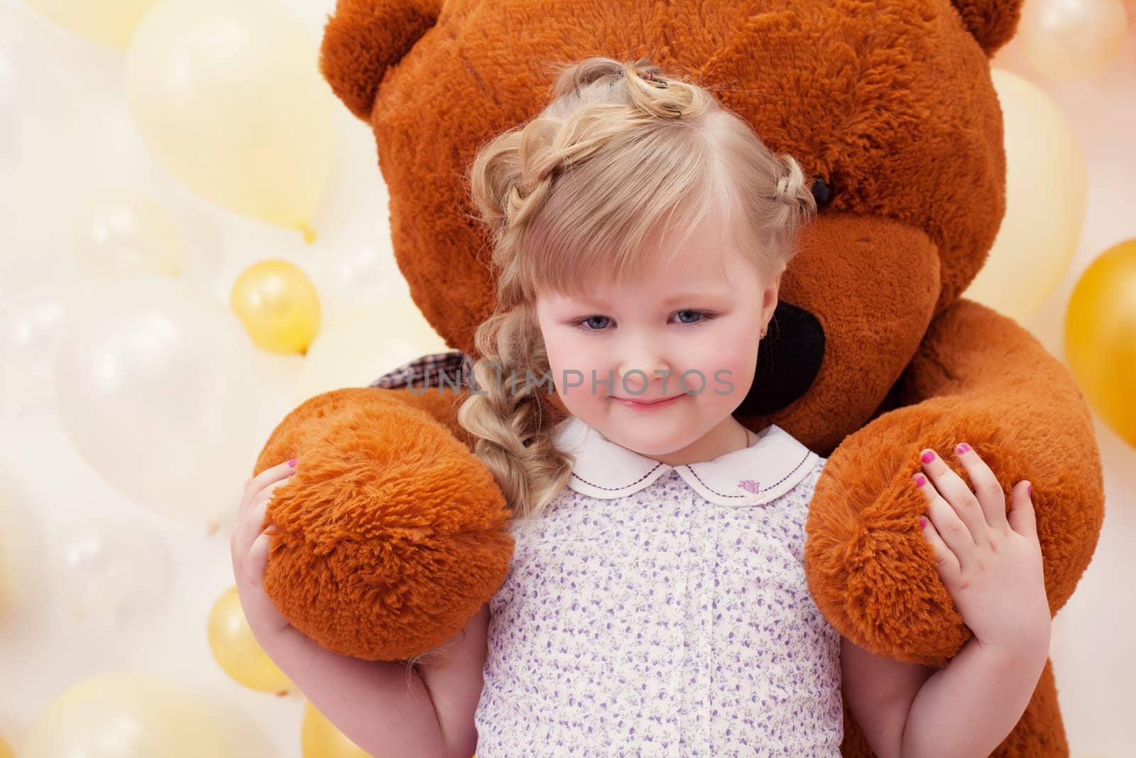 Cute little girl in arms of large teddy bear, close-up
