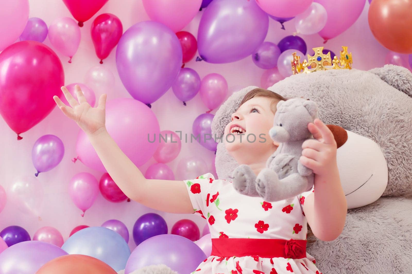 Joyful little girl playing with teddy bears in playroom