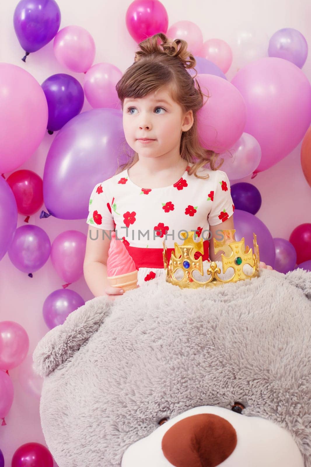 Studio shot of amusing little girl posing with big teddy bear