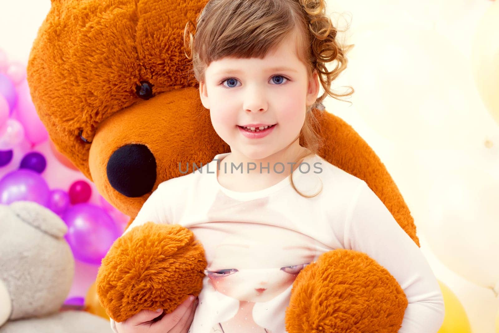 Pretty little girl posing in arms of big plush bear