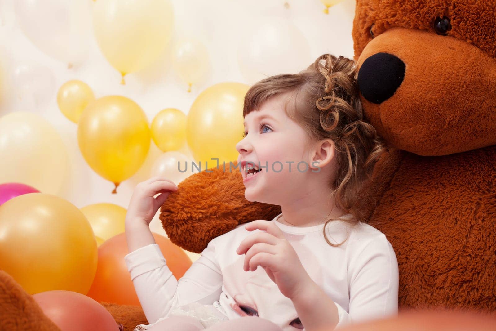 Joyful little girl posing hugging plush bear, close-up