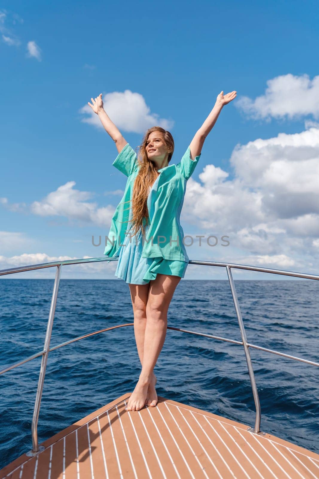 Woman on a yacht. Happy model in a swimsuit posing on a yacht against a blue sky with clouds and mountains by Matiunina