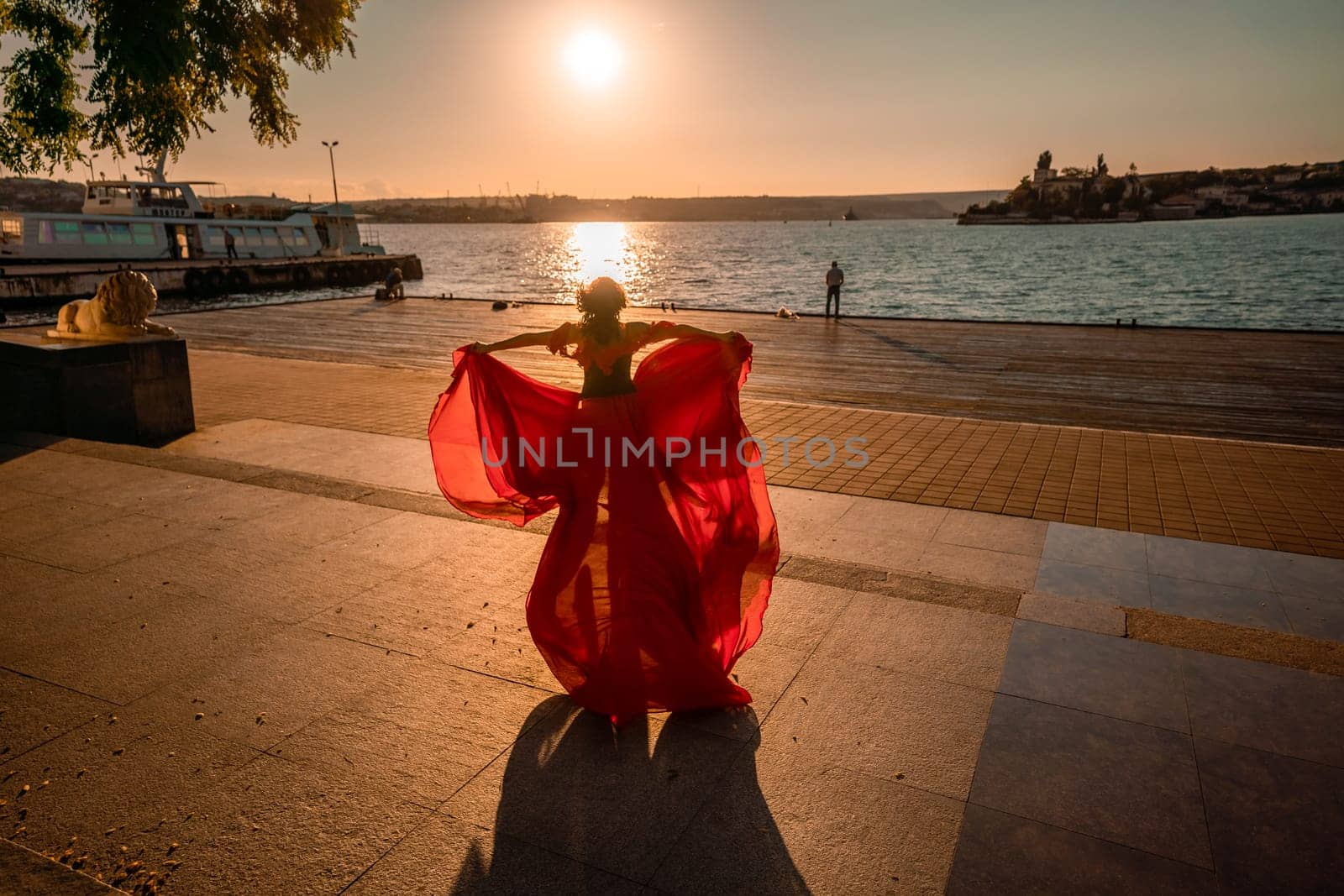 Sunrise red dress. A woman in a long red dress against the backdrop of sunrise, bright golden light of the sun's rays. The concept of femininity, harmony. by Matiunina