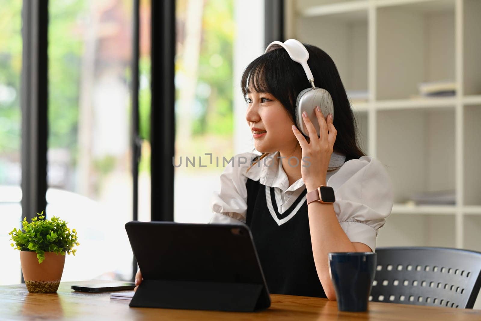 Thoughtful asian student woman listening music in wireless headphones and looking away. People, technology and lifestyle concept.