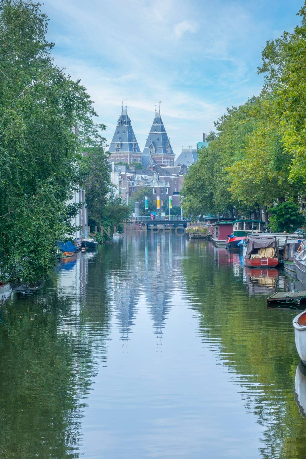 Netherlands. Early summer morning on the Amsterdam canal. Many moored boats and the roof of the cathedral in the background