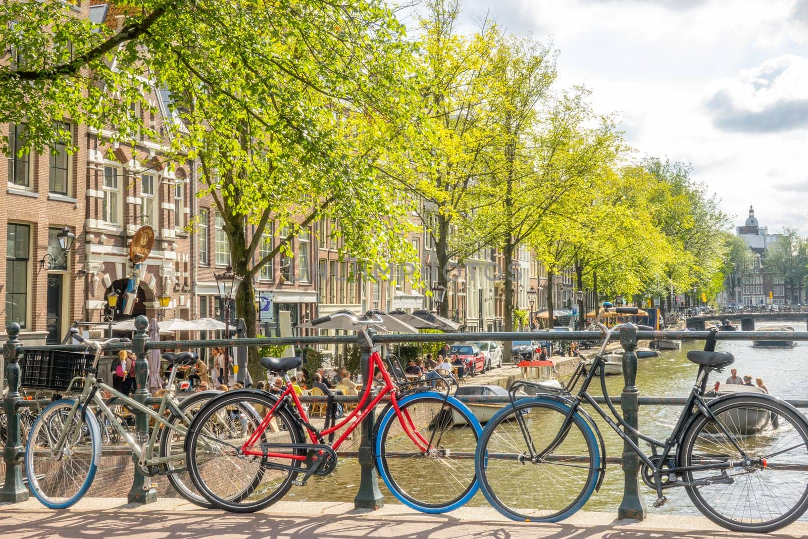 Netherlands. Sunny summer day in Amsterdam. Parked bicycles on the bridge over the canal. Small street cafe on the waterfront