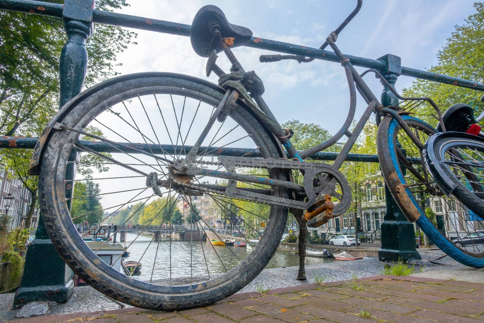 Netherlands. Summer day in Amsterdam. Dirty old bicycle near the canal fence