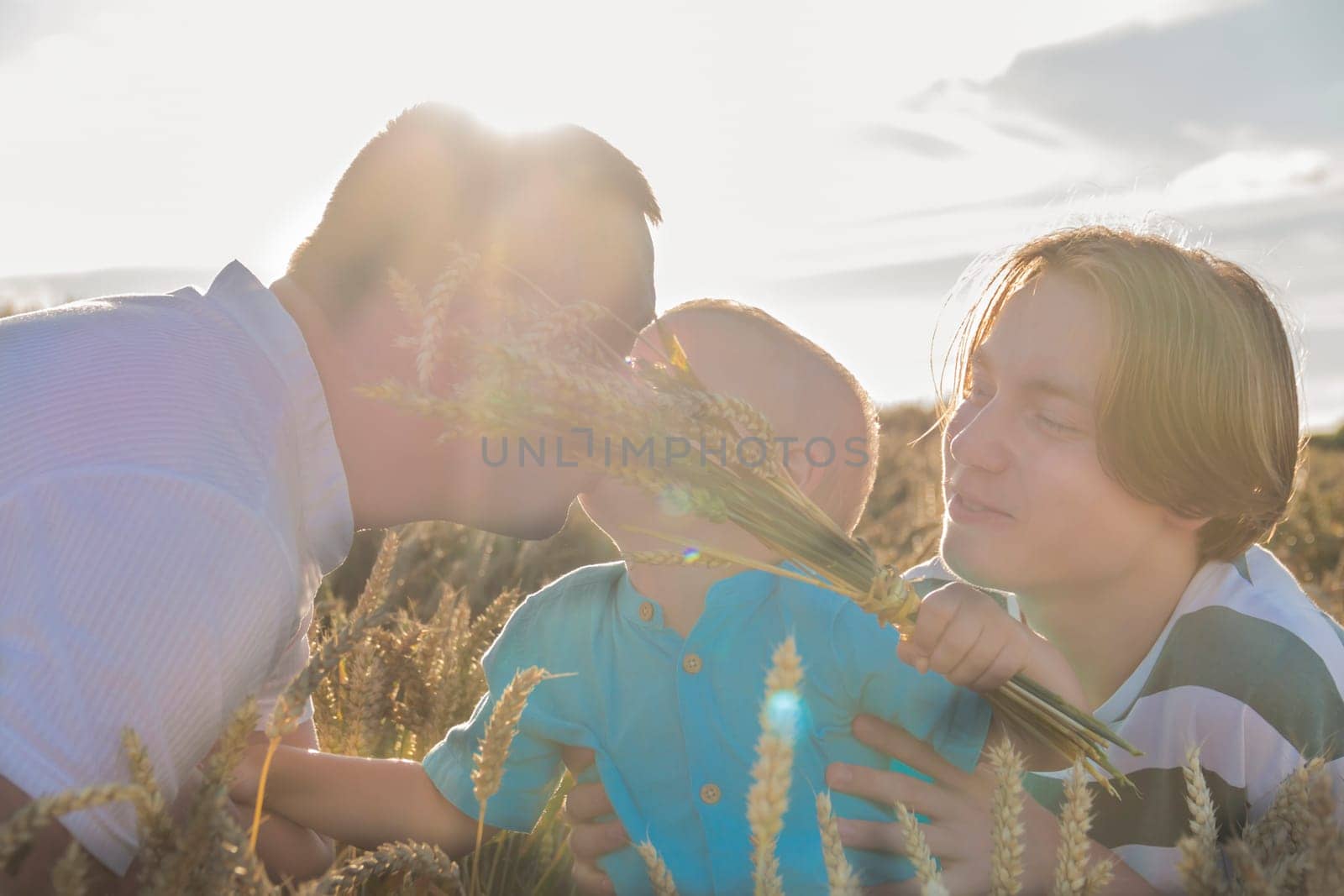 A family with a dad, a teenager and a small child are walking carefree and fun in a field with wheat. It's time to harvest. The food crisis in the world. by Alla_Yurtayeva