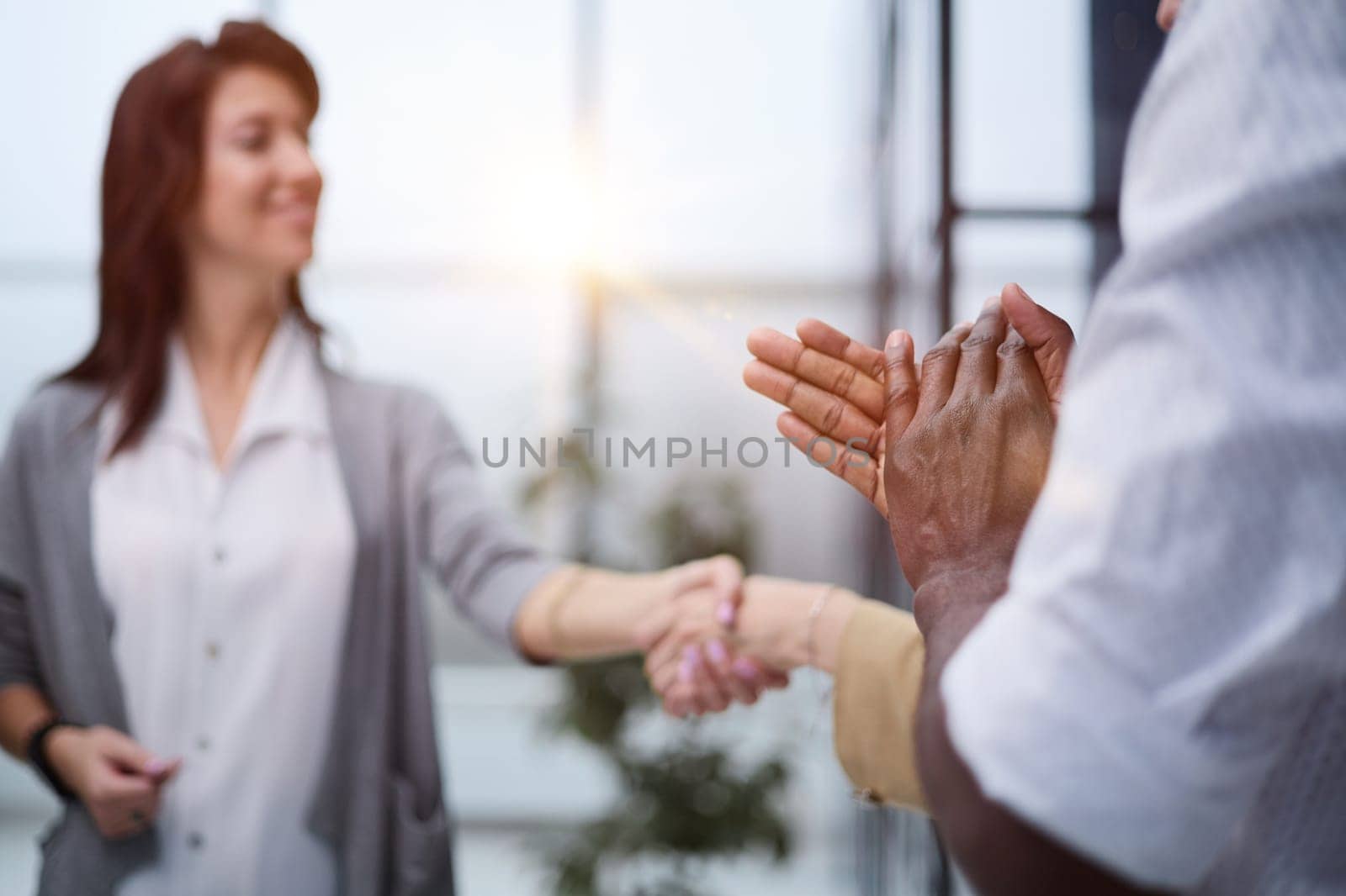 Two professional business people shaking hands in an office lobby