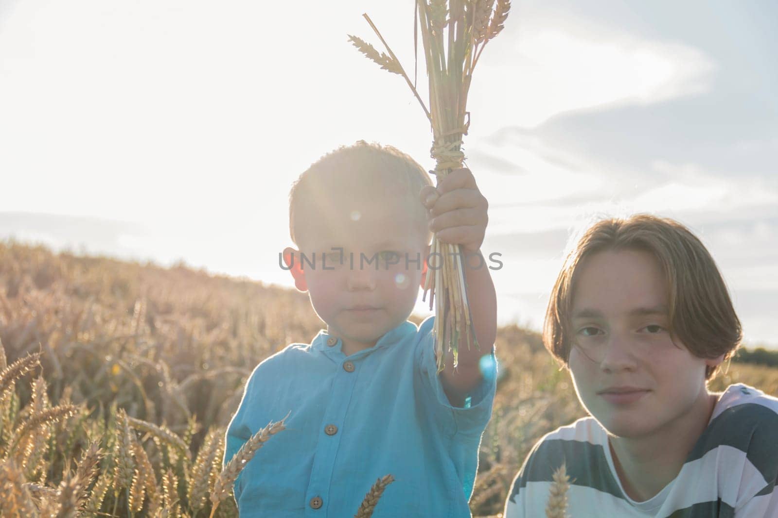 A little boy and his teenage brother are having fun walking in a field with ripe wheat. Grain for making bread. the concept of economic crisis and hunger
