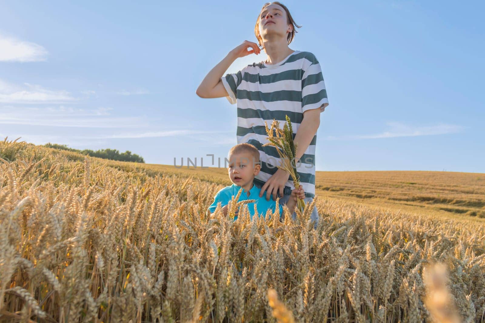 A little boy and his teenage brother are having fun walking in a field with ripe wheat. Grain for making bread. the concept of economic crisis and hunger