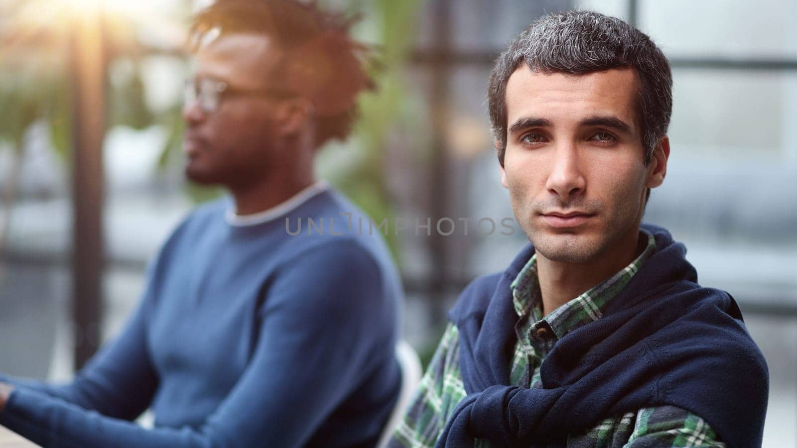 Close-up portrait of a handsome successful businessman in the office against the background of his African-American colleague