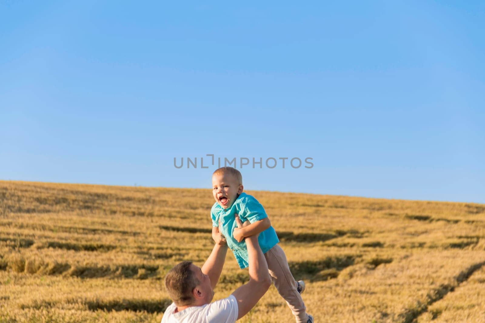 Dad and his little son are having fun walking in a field with ripe wheat. Grain for making bread. the concept of economic crisis and hunger. by Alla_Yurtayeva