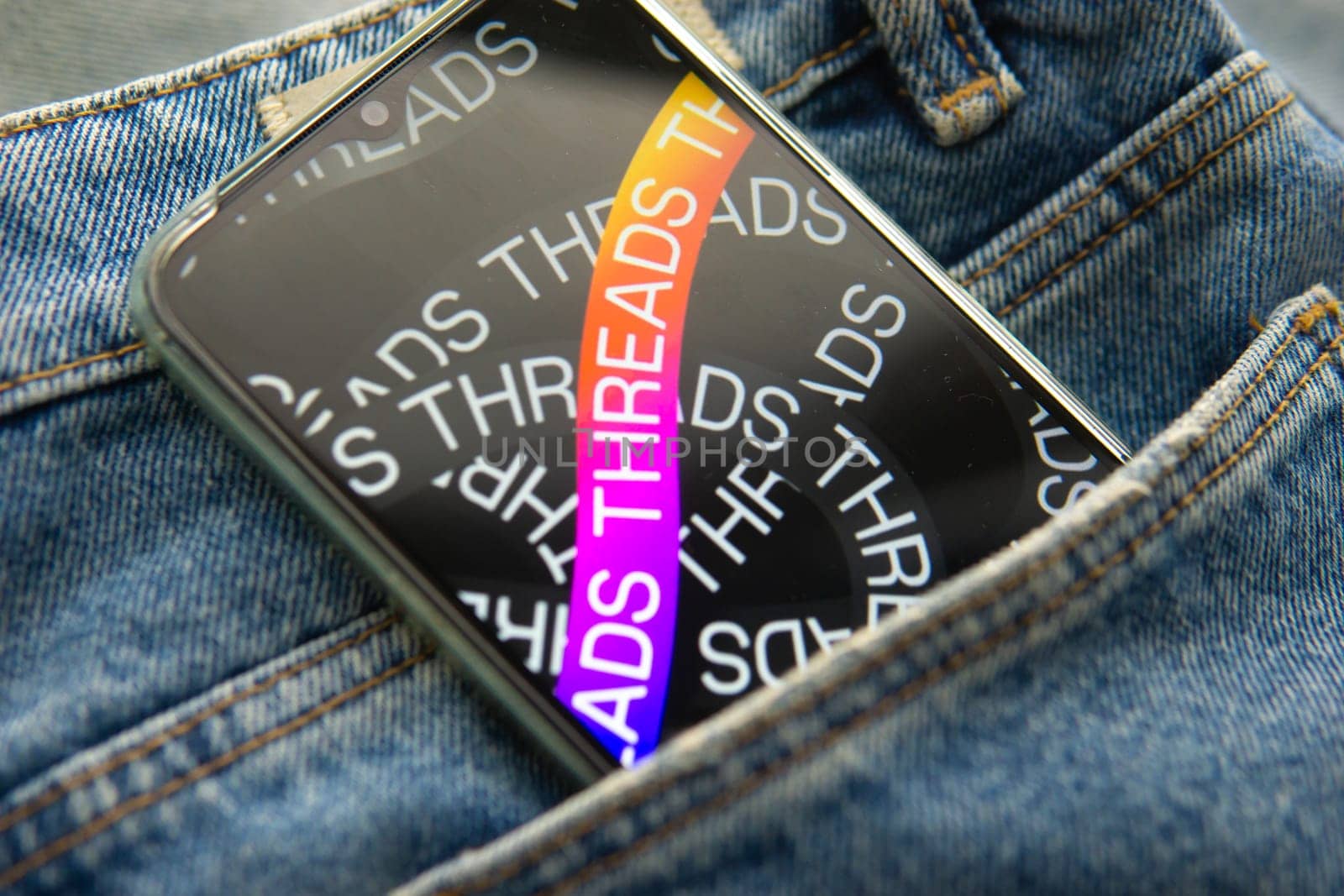 Tver, Russia - July 15, 2023, the threads logo on the smartphone screen lying on the jeans. The threads icon. The logo of the current application. Threads social network