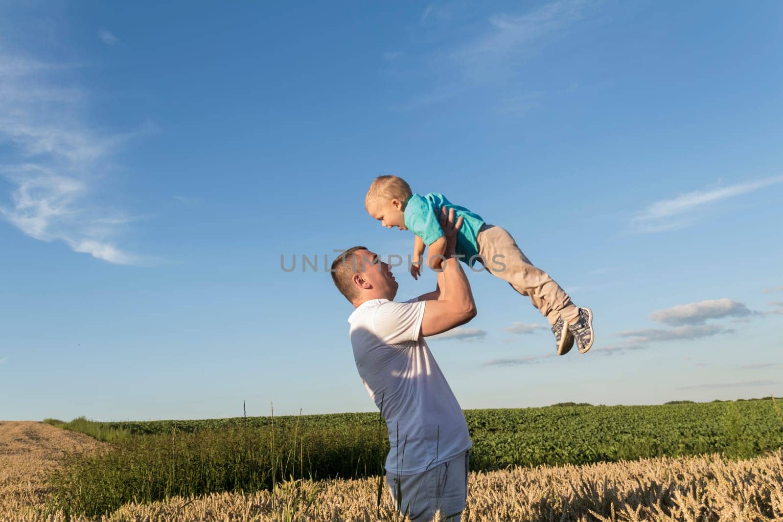 Dad and his little son are having fun walking in a field with ripe wheat. Grain for making bread. the concept of economic crisis and hunger. by Alla_Yurtayeva