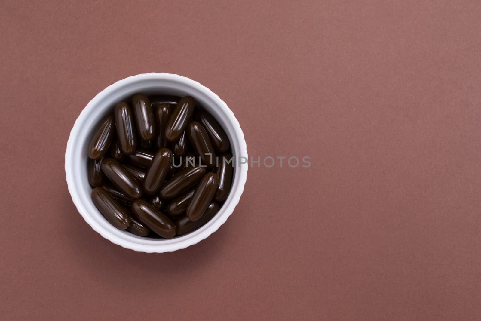 Top View Sunflower Lecithin Brown Softgel Pill Capsule In White Bowl On Brown Background. Vitamin, Dietary Supplements. Copy Space. Lecithin Benefits For Skin, Digestion, Lower Cholesterol. Horizontal