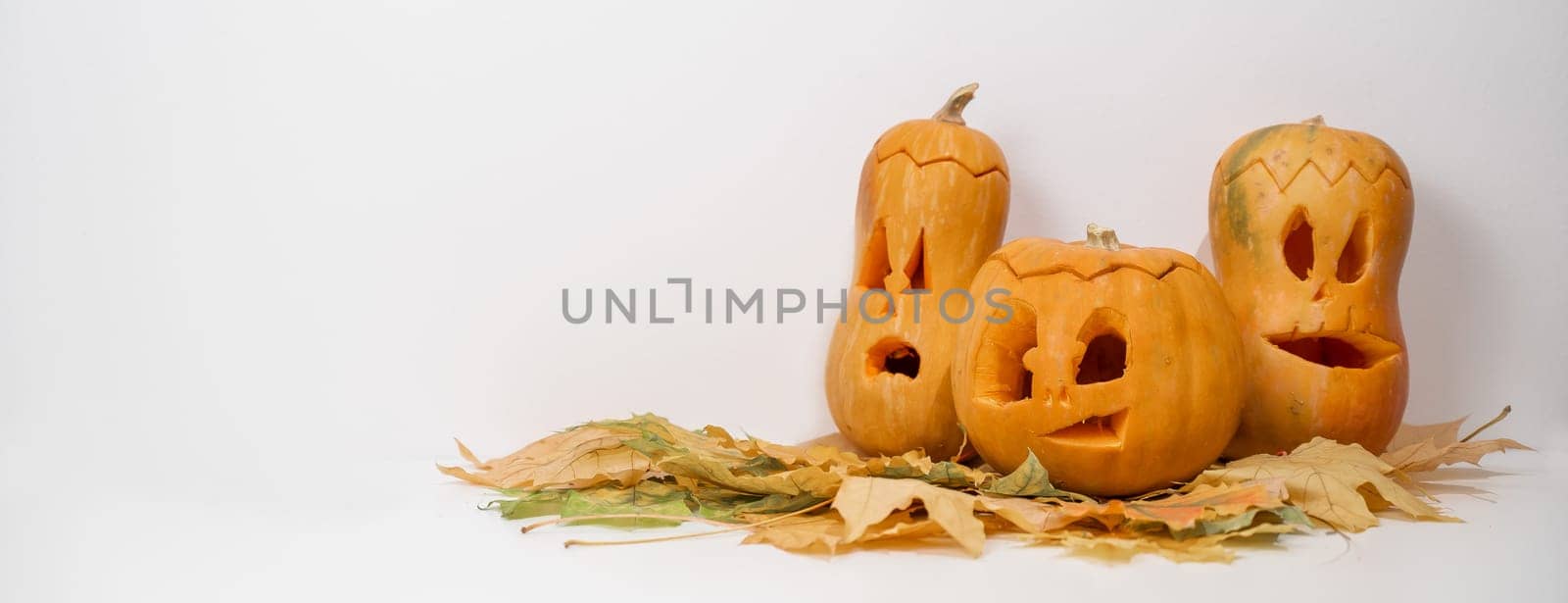 Group of jack-o-lantern on maple leaves. Halloween decoration on a white background