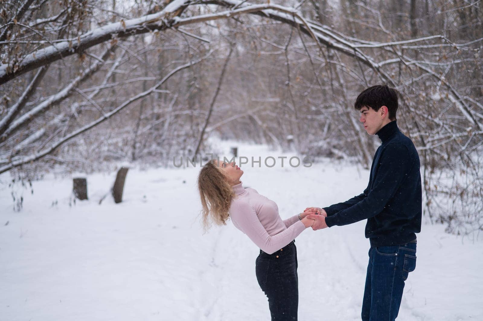 A young couple walks in the park in winter without jackets
