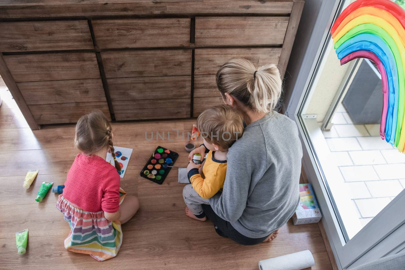 Mother and kids painting a rainbow on the window