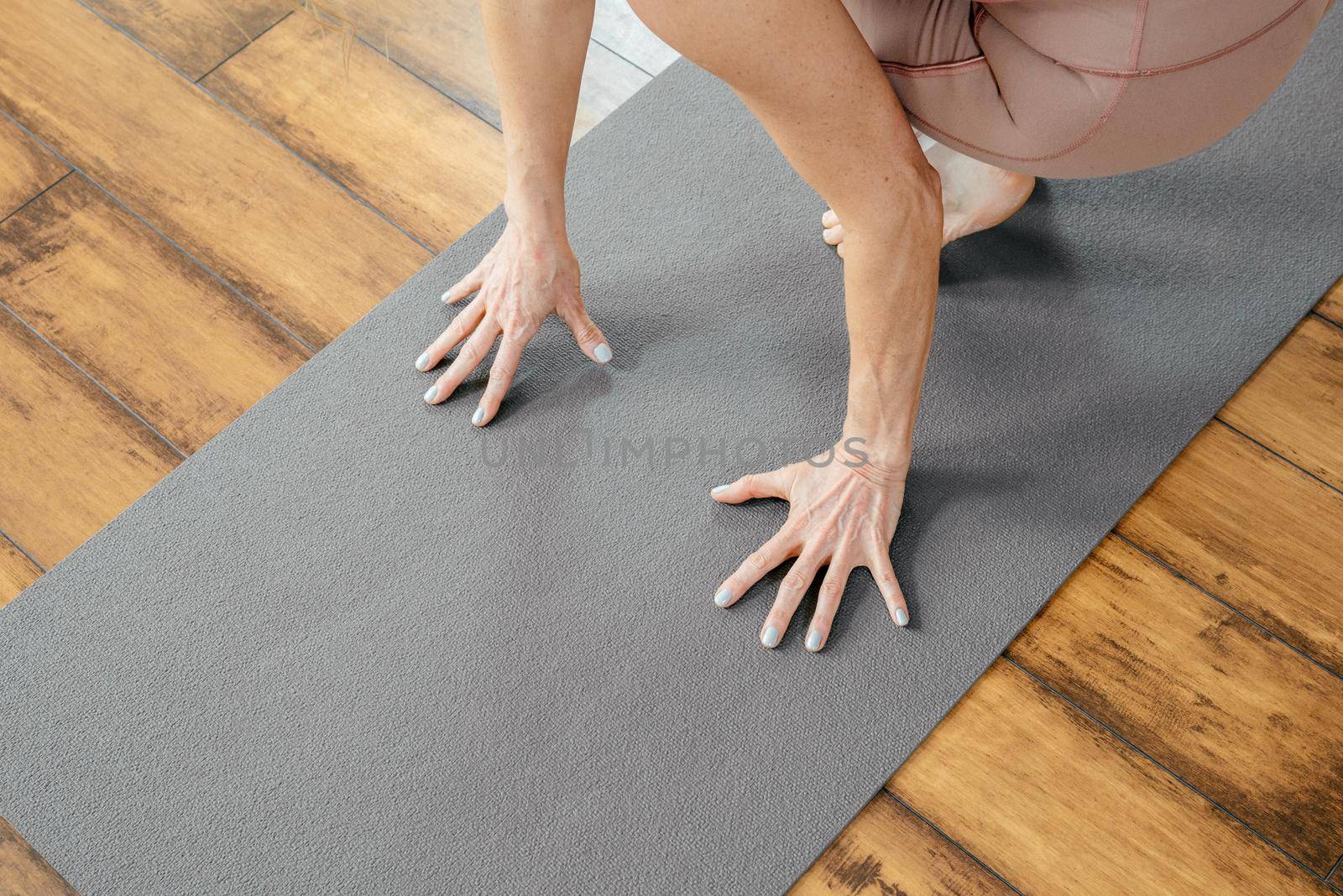 Cropped view of mature woman doing yoga or pilates on a mat in yoga studio