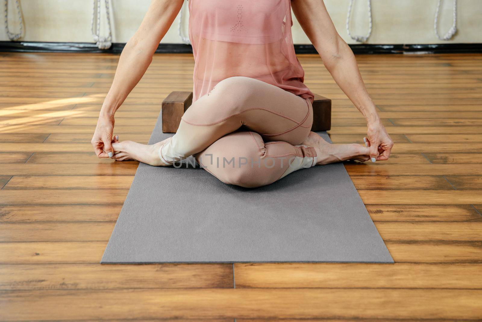 Mature strong woman doing yoga or pilates stretching relaxation exercise in white loft studio interior. Breathing, concentrating, healthy lifestyle concept by Mariakray