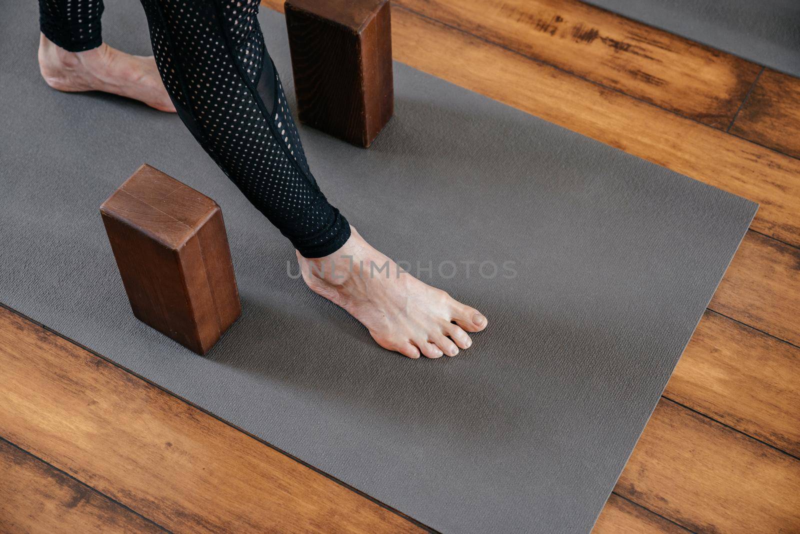Cropped view of woman stretching her legs in yoga studio with yoga blocks by Mariakray