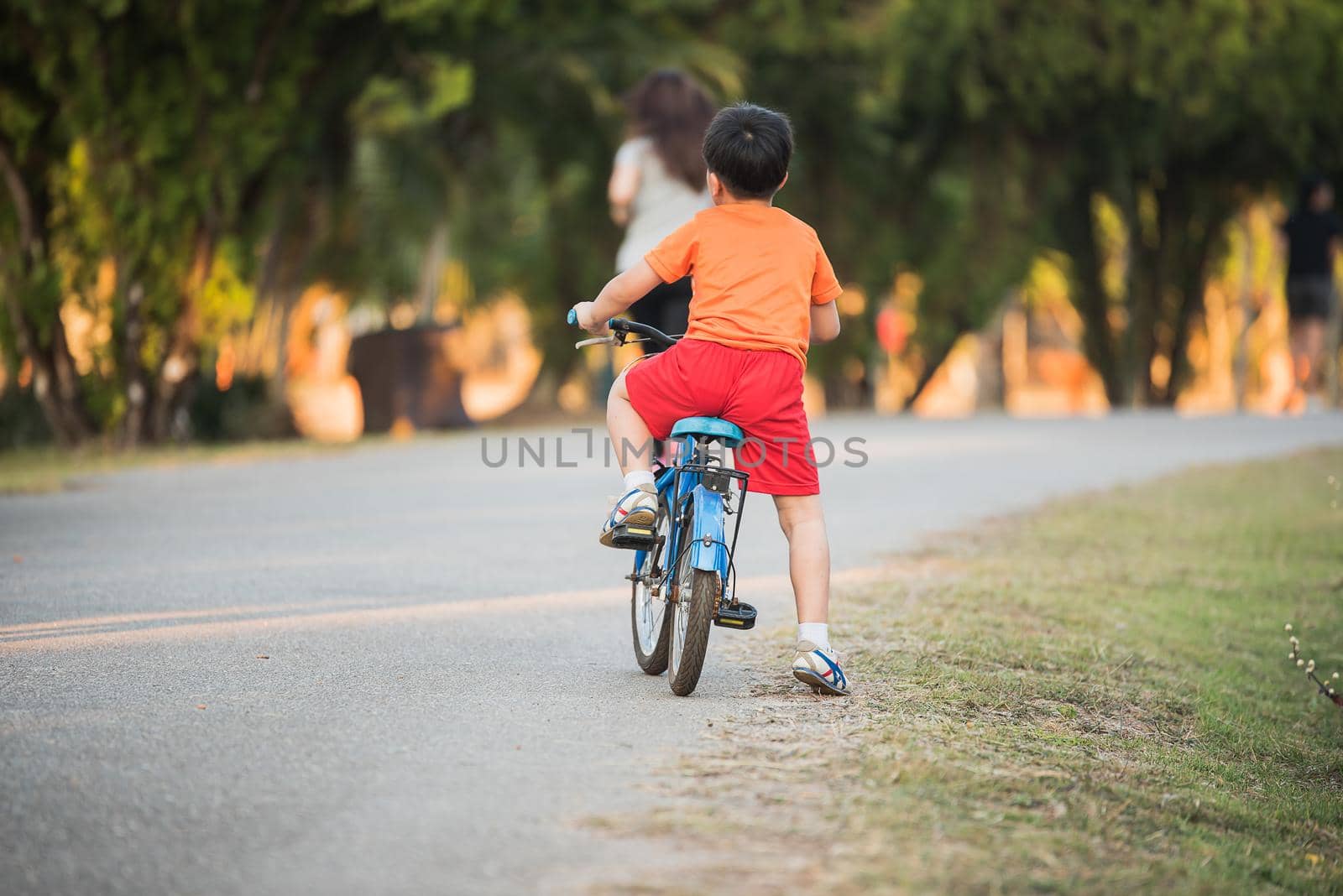 Young Asian boy ride a bicycle on the road by Wmpix