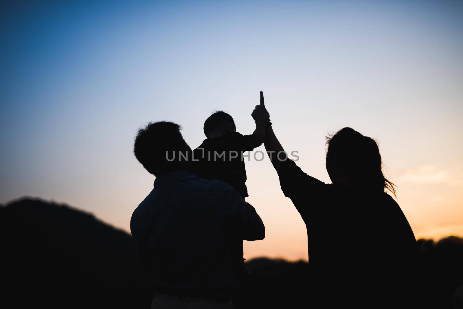 silhouette of family at sunset by Wmpix